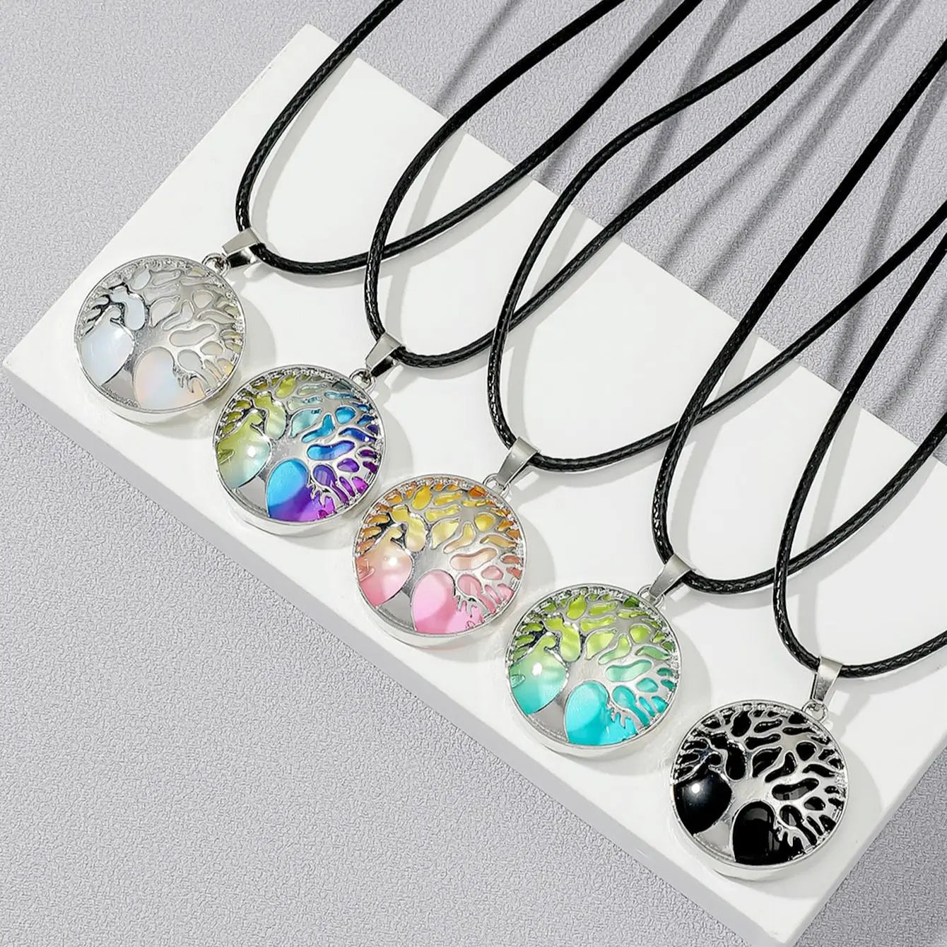 Set of tree of life necklaces with colorful designs on a white surface
