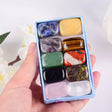 Hand holding a box of multicolored stones against a blurred natural background
