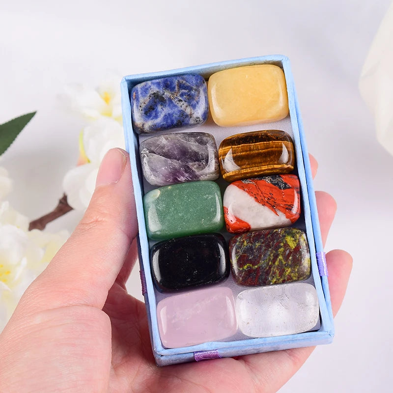 Hand holding a box of multicolored stones against a blurred natural background