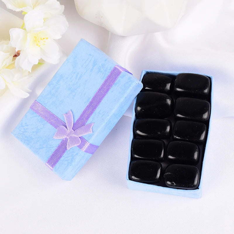 Black stones in a blue box with a purple ribbon on a white background