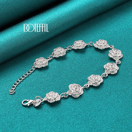 Silver bracelet with floral designs on a teal fabric background