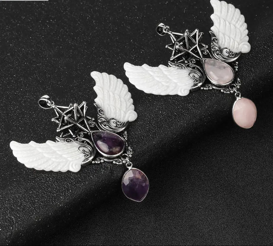 Jewelry set with angel wing pendants and gemstones on a dark background