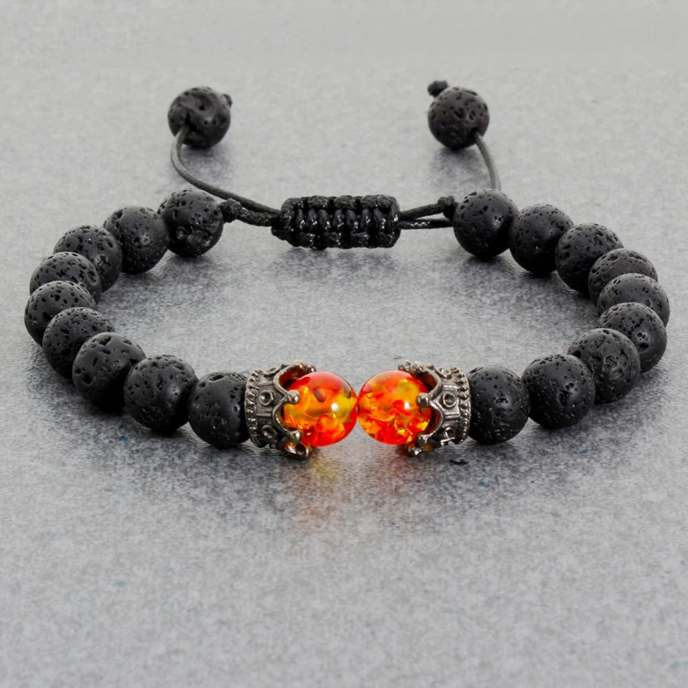 Black beaded bracelet with two orange beads on a gray surface