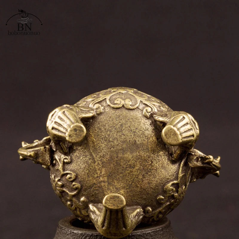 Bronze decorative object with intricate designs on a dark background