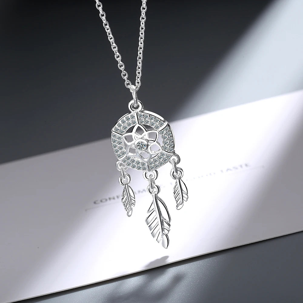 Silver necklace with a dreamcatcher pendant on a reflective surface