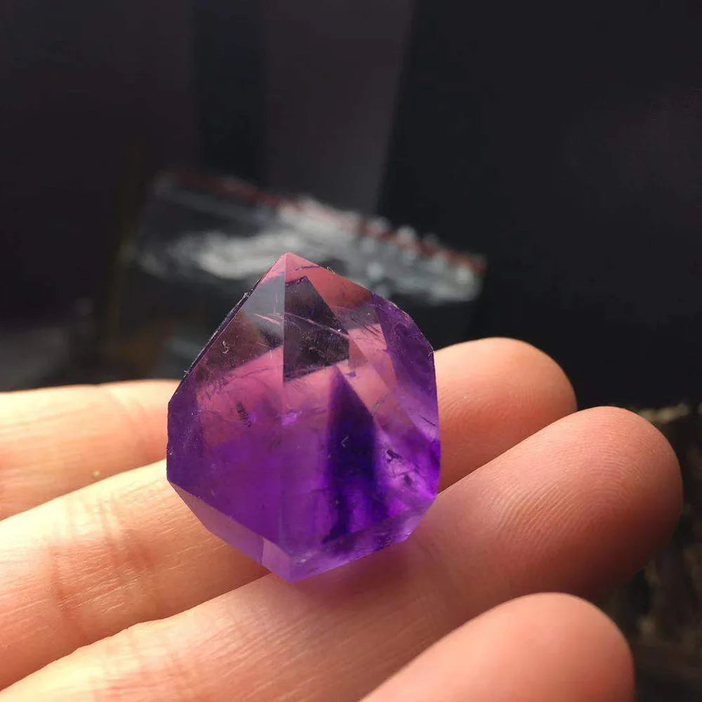 Hand holding a purple crystal with a blurred background