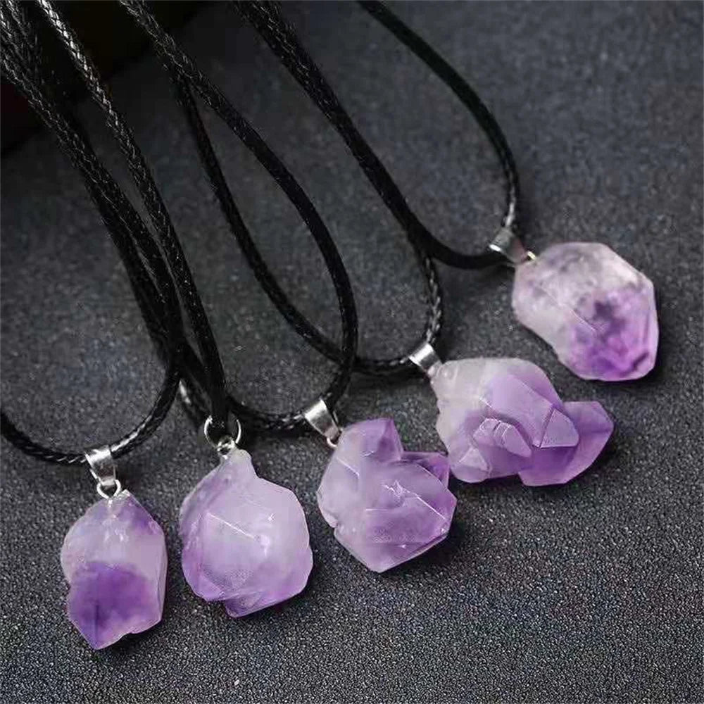 Purple crystal pendants on black cords against a dark background