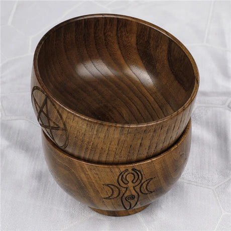 Two wooden bowls with engraved designs on a white textured background