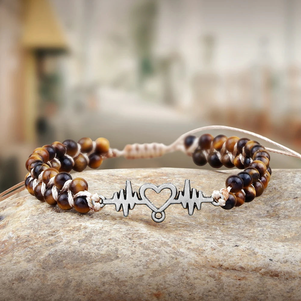 Beaded bracelet with a heart rate design on a stone surface