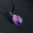Purple crystal pendant on a black cord against a dark background