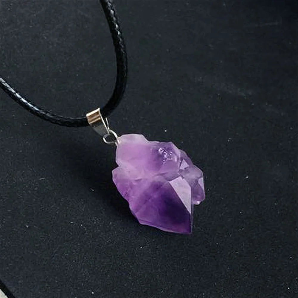 Purple crystal pendant on a black cord against a dark background