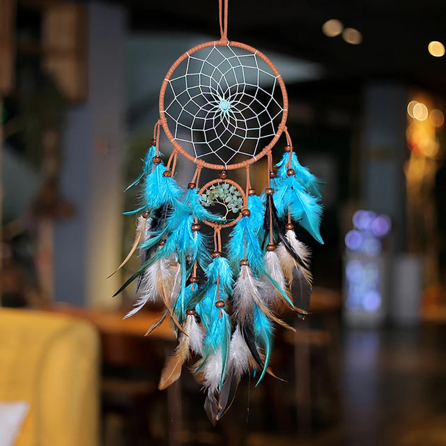 Dreamcatcher with blue feathers against a blurred indoor background