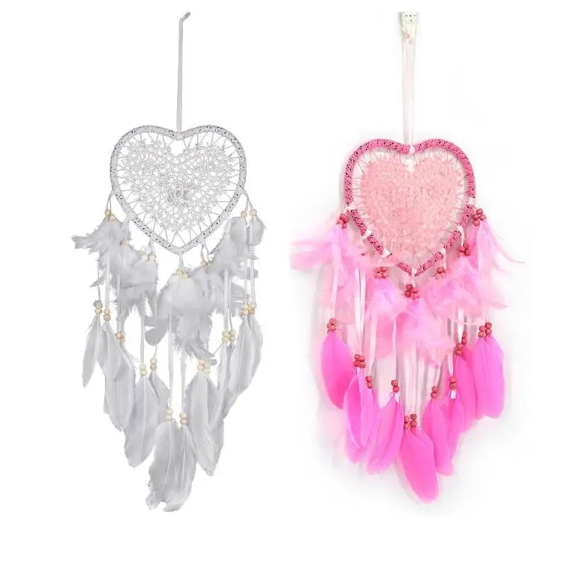 Two heart-shaped dream catchers, one silver and one pink with feathers, on a white background.