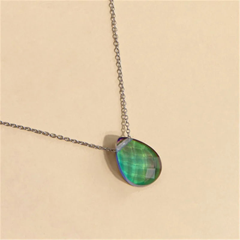 Necklace with a green teardrop pendant on a beige background