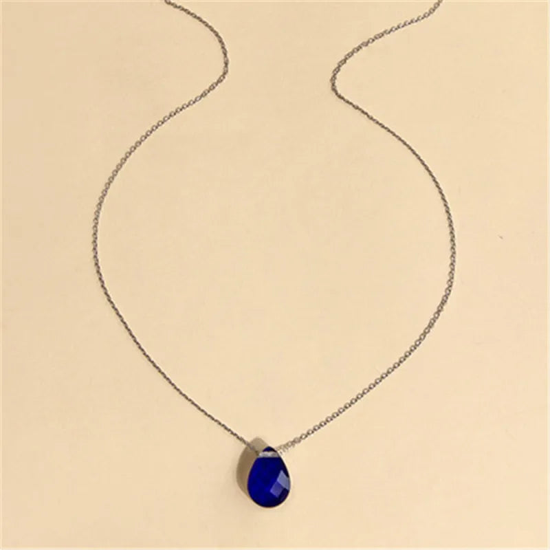 Necklace with a blue teardrop pendant on a beige background