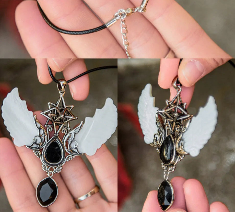 Necklace with angel wing pendant held by a hand, close-up view.
