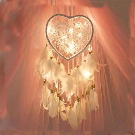 Heart-shaped dreamcatcher with lights against a soft pink background