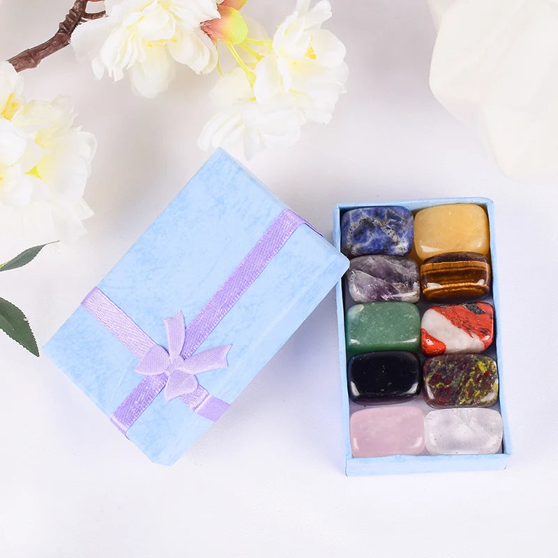 Box of multicolored stones with a decorative ribbon on a light background