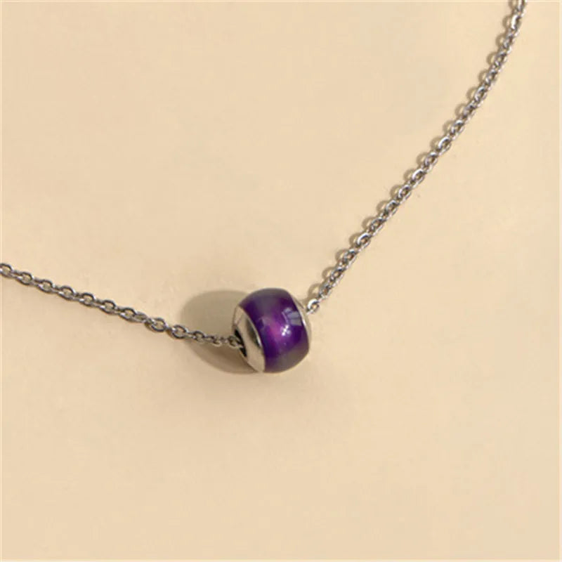 Necklace with a purple and silver bead on a beige background