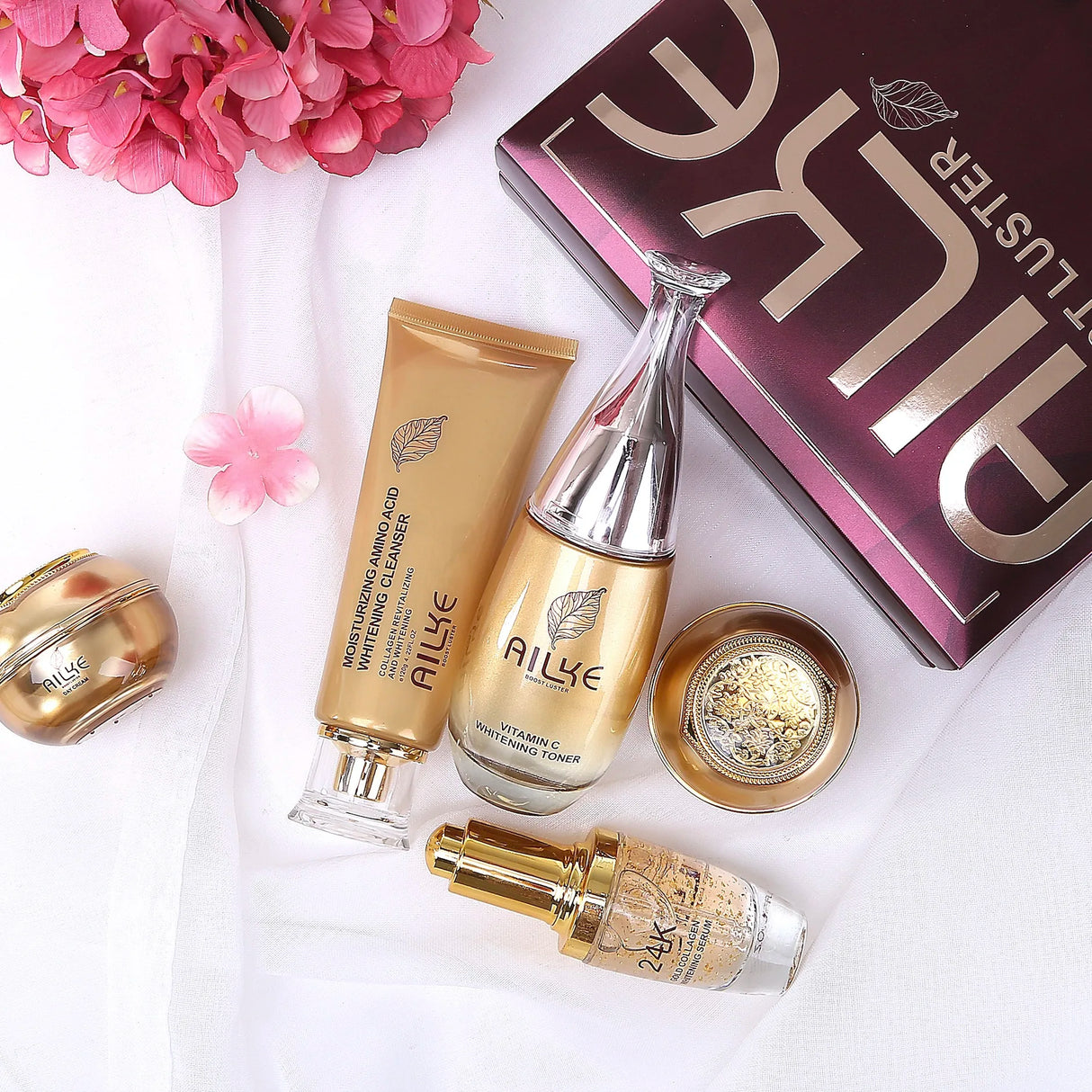 Allue skincare products including a bottle, tube, and box on a white background with pink flowers.