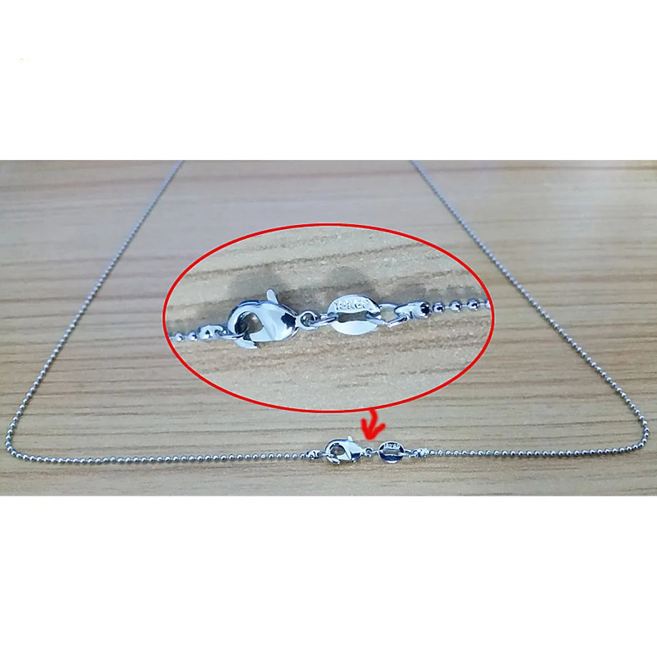 Silver chain with a close-up of a clasp on a wooden surface, featuring the SJA brand logo.