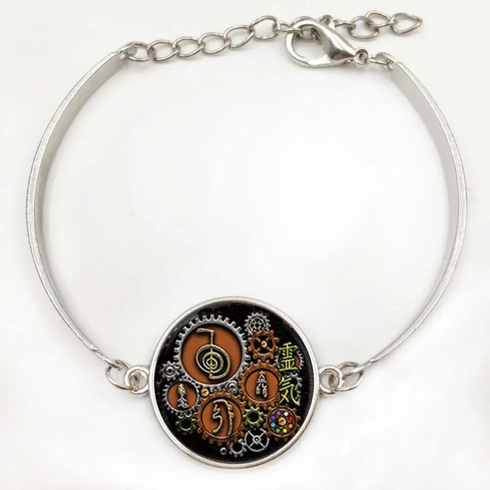 Silver bracelet with a circular emblem featuring intricate designs and symbols on a white background