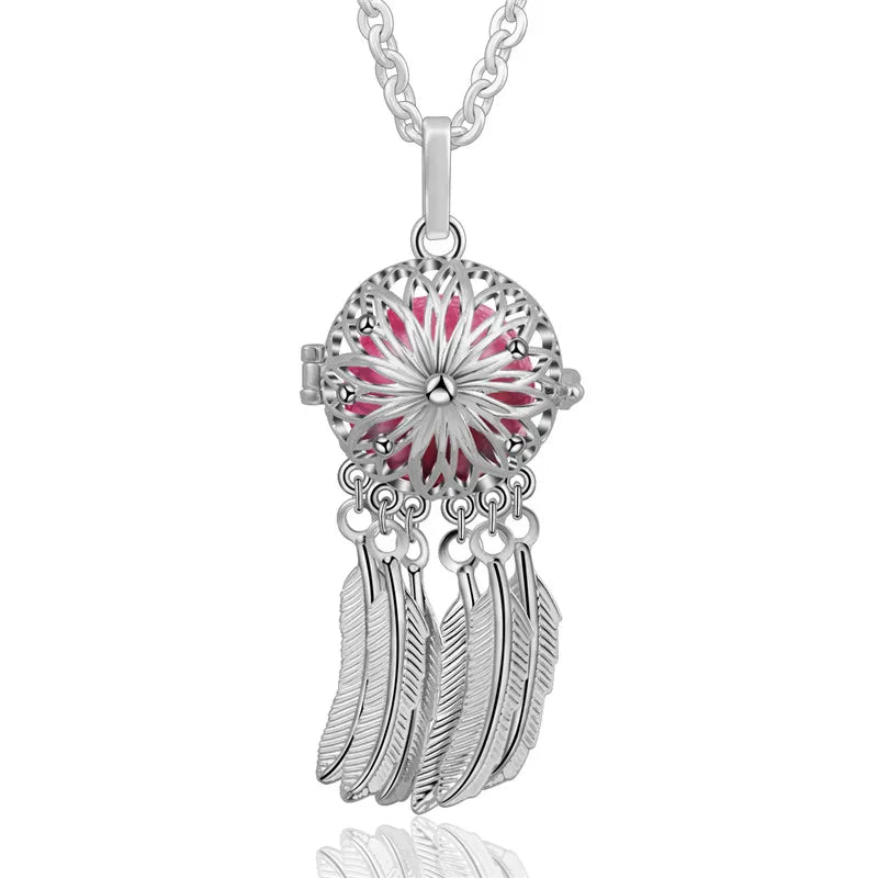 Silver dreamcatcher pendant with pink center and feathers on a white background