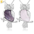 Two owl-shaped necklaces with purple and pink stones on a white background