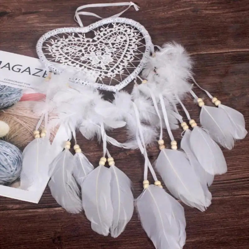 Heart-shaped dreamcatcher with white feathers on a wooden surface
