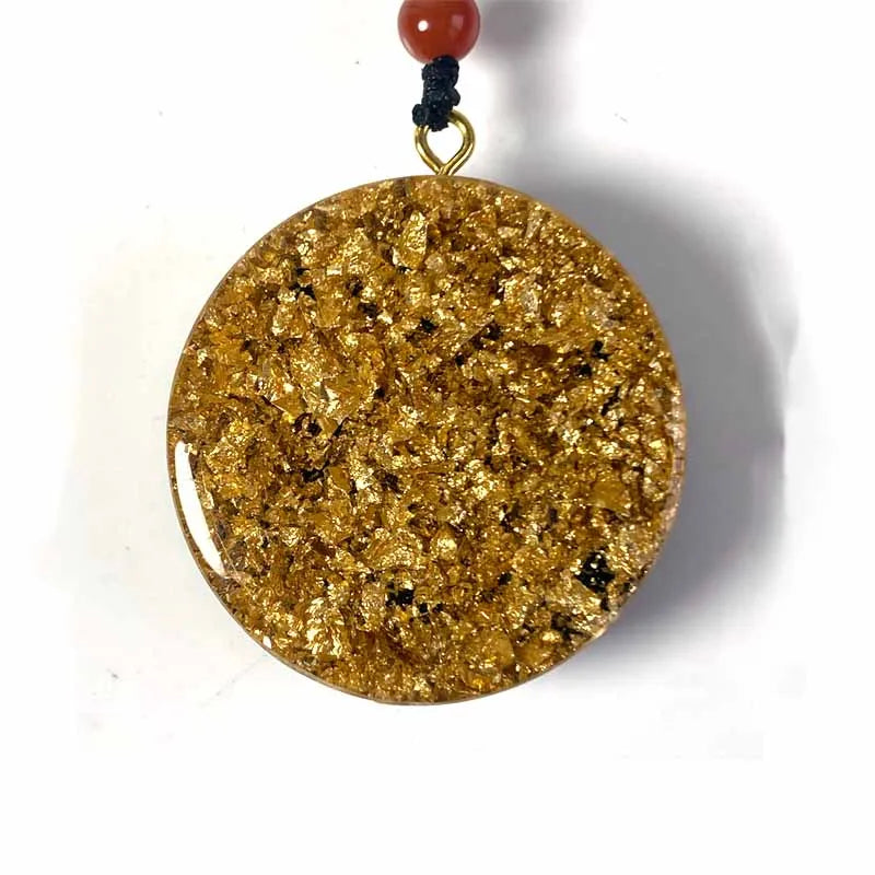 Gold pendant with a red bead on a white background