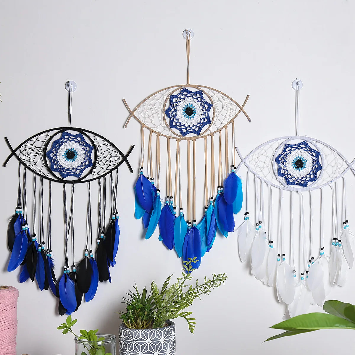 Three dream catchers with blue and black feathers, blue and white feathers, and white feathers on a white background.