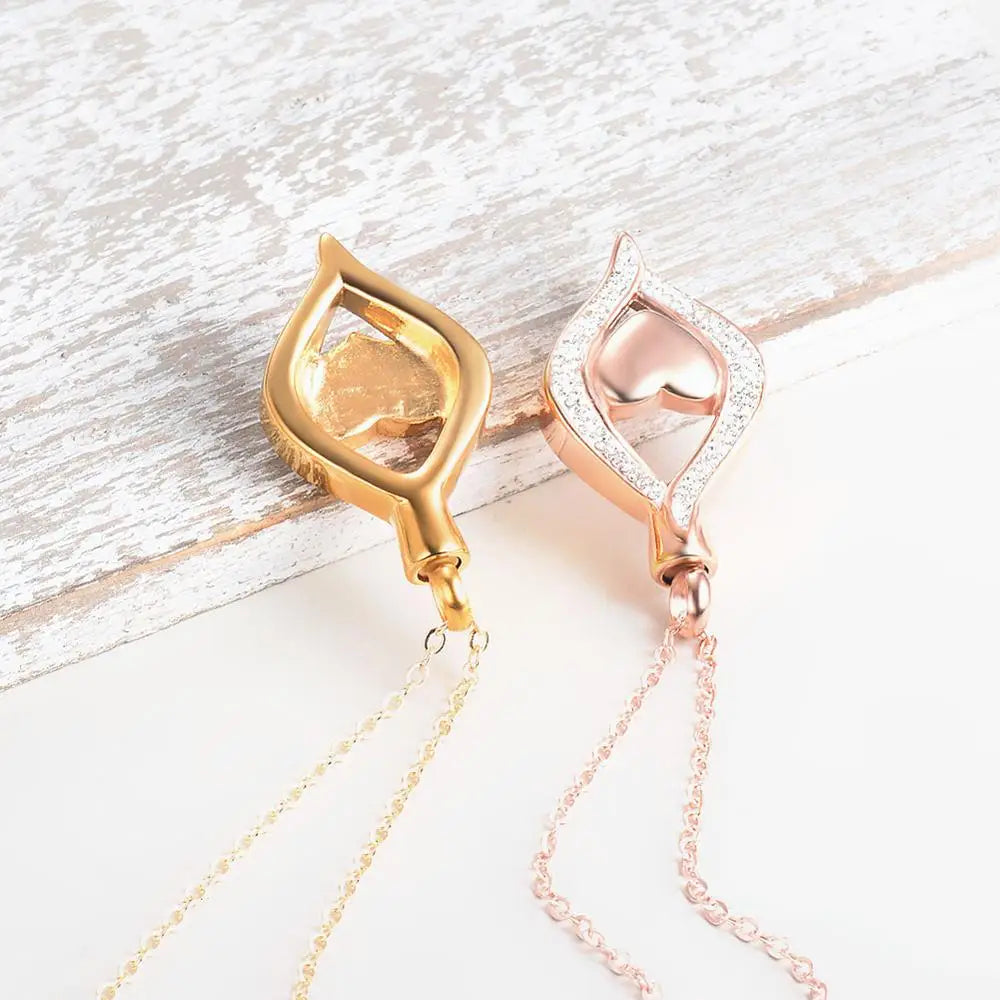 Gold and rose gold necklaces with teardrop-shaped pendants on a light wooden surface.