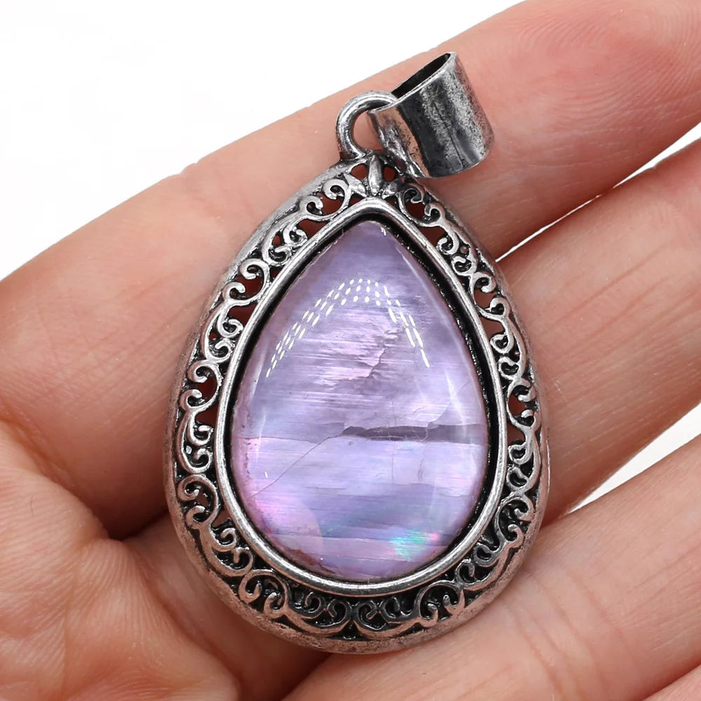 Teardrop-shaped purple gemstone pendant with silver frame held in hand