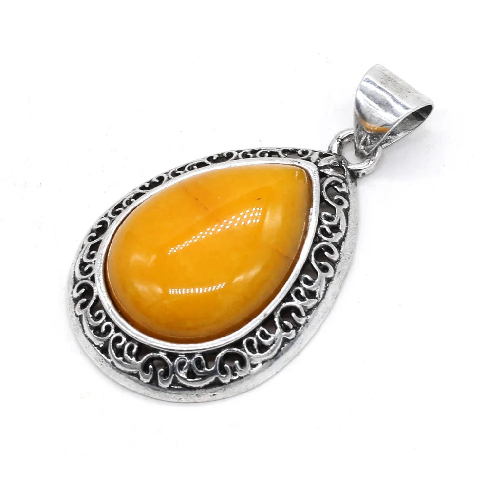 Silver pendant with a yellow teardrop-shaped gemstone on a white background