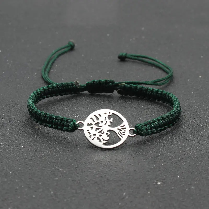 Green braided bracelet with a silver tree of life charm on a dark background