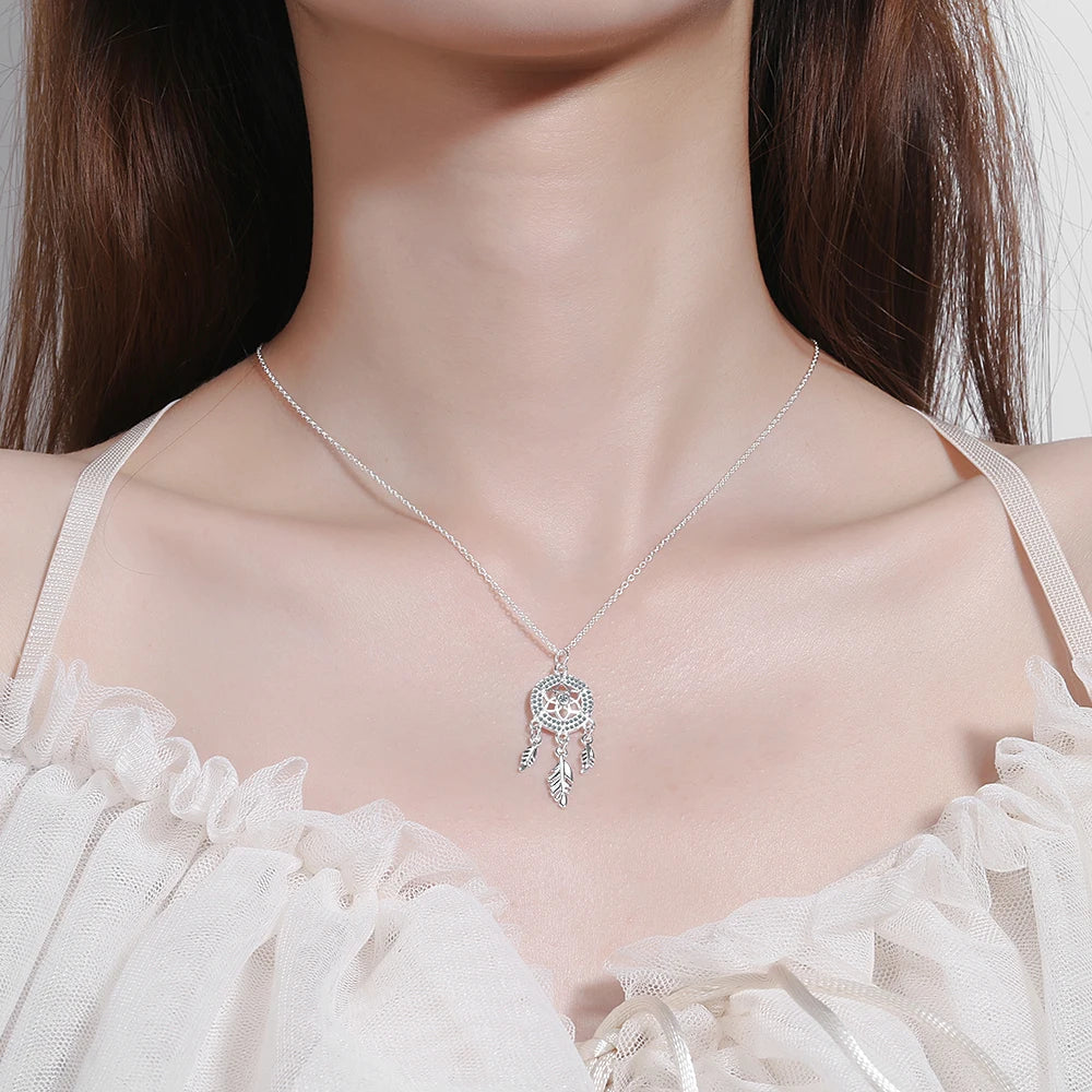 Silver necklace with a pendant worn by a model in a white dress.