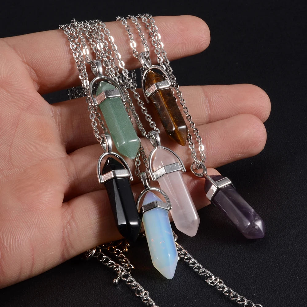 Hand holding a set of crystal pendant necklaces on a black background