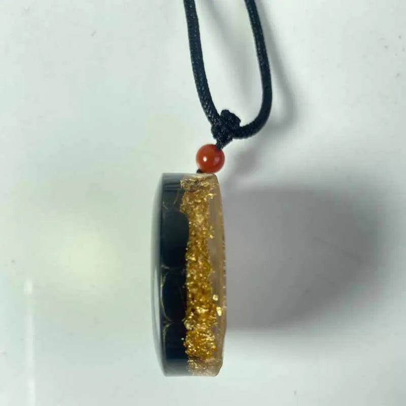 Necklace with a pendant featuring gold and black design on a white background