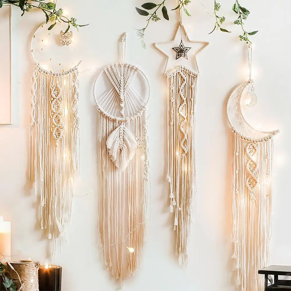 Set of four decorative dreamcatchers hanging on a wall with candles and greenery.
