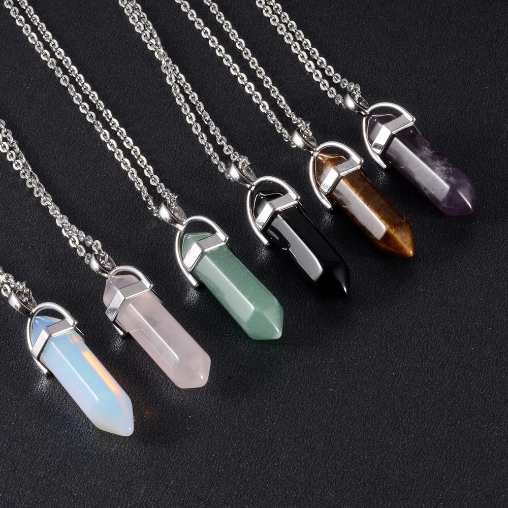 Crystal pendant necklaces on silver chains against a black background
