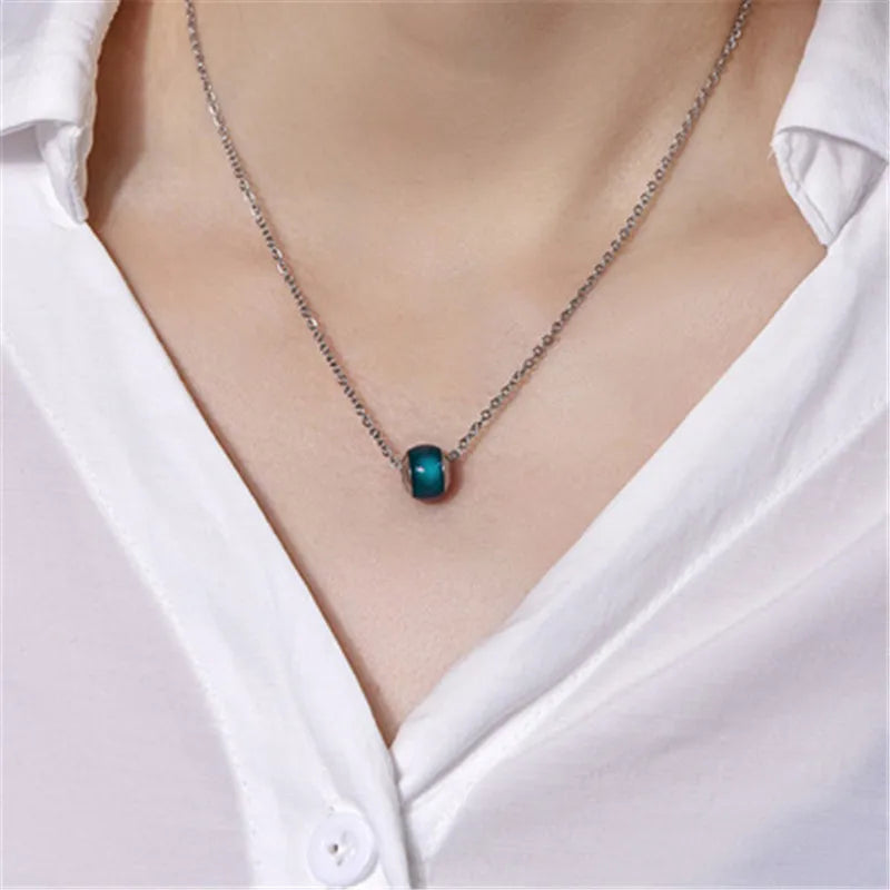 Necklace with a green pendant worn by a person in a white shirt