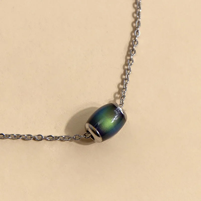 Necklace with a green and black beaded pendant on a beige background