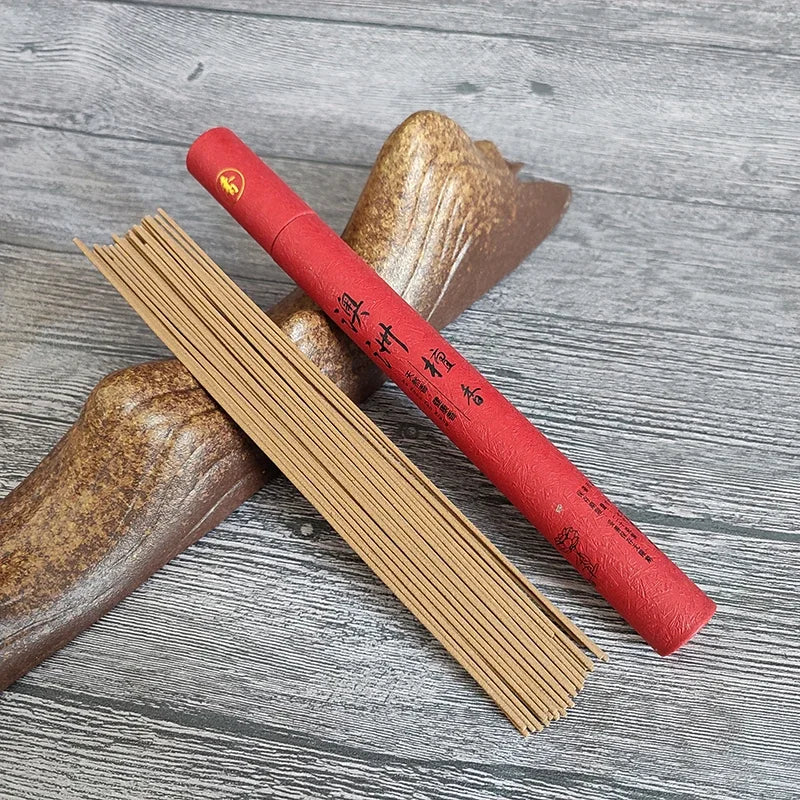 Red incense stick holder with incense sticks on a wooden surface
