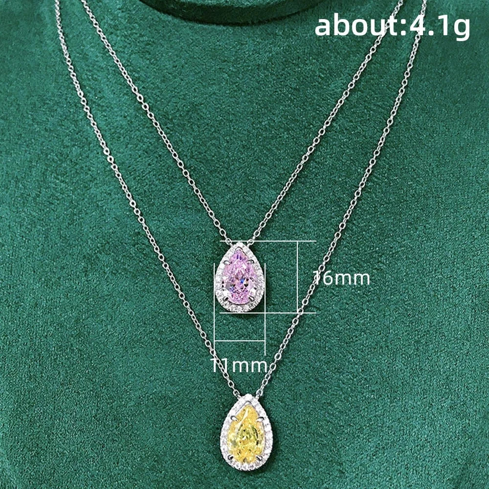 Two silver necklaces with teardrop-shaped gemstones on a green background