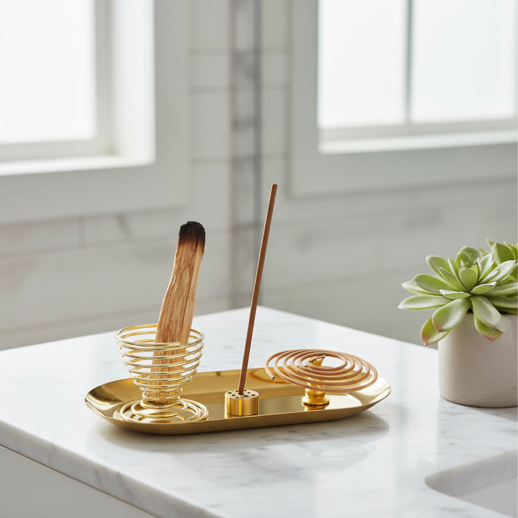Gold incense burner with a single incense stick on a white background