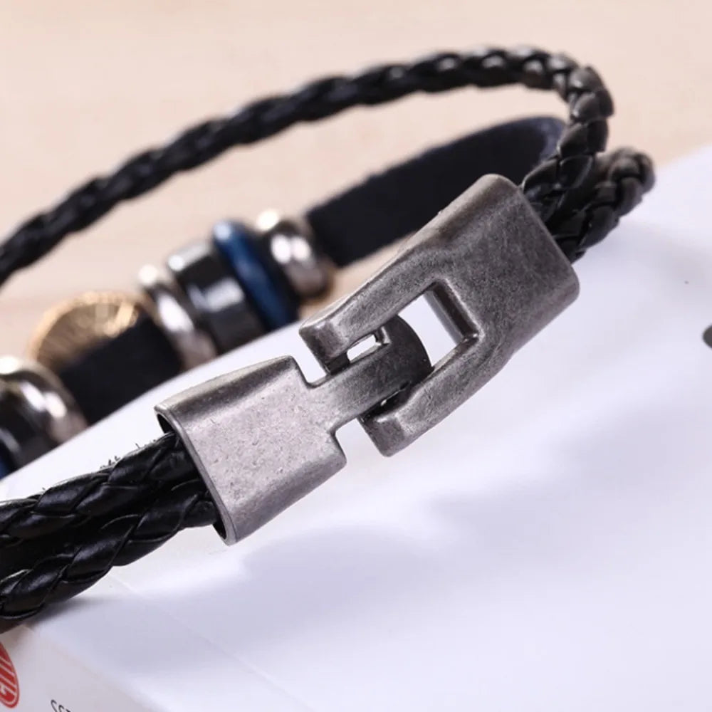 Close-up of a black braided leather bracelet with a silver clasp on a blurred background