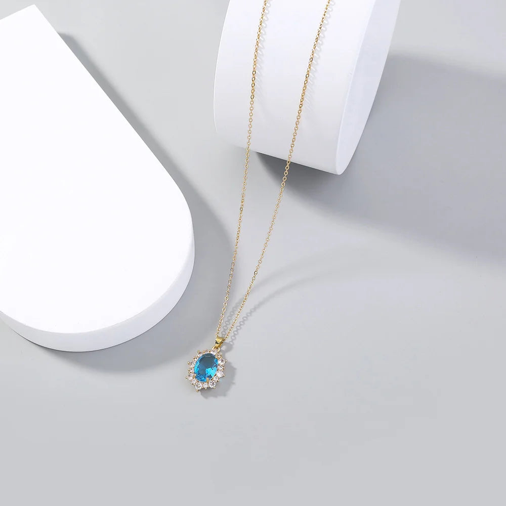 Gold necklace with a blue gemstone pendant on a light gray background
