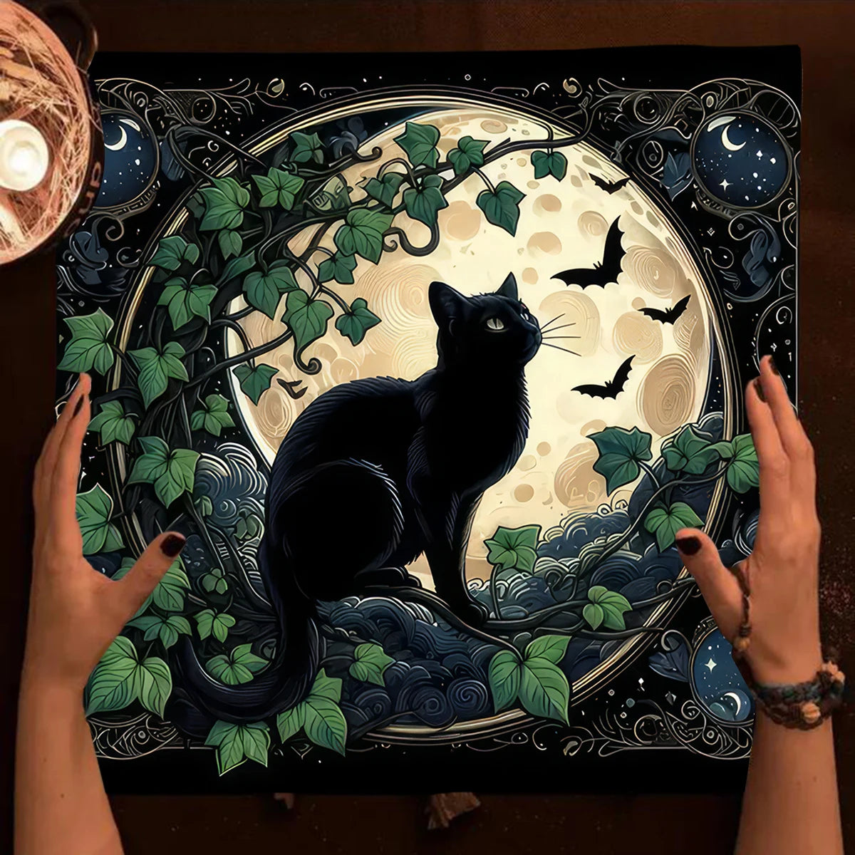 Decorative mat with a black cat design, hands holding it, and a candle on the side.