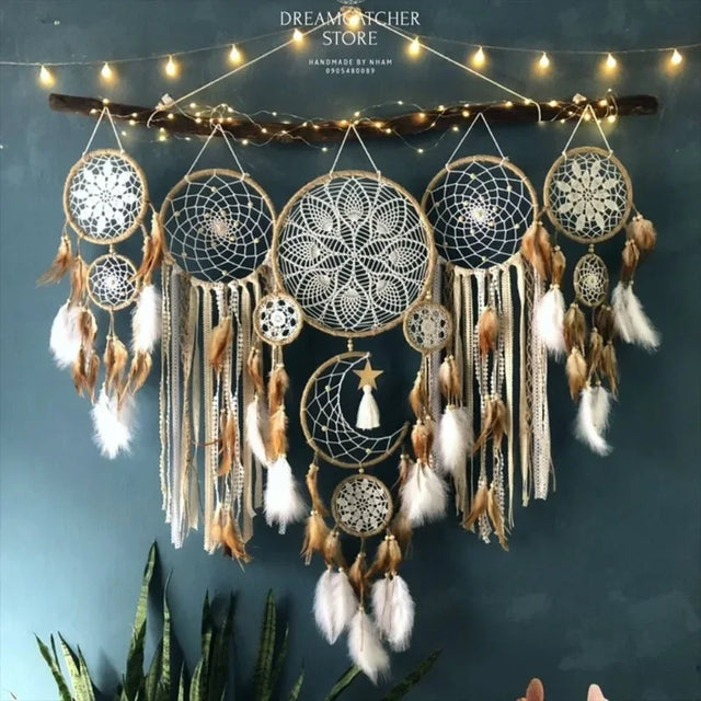 Decorative dreamcatcher with feathers and beads hanging against a dark blue wall with string lights.