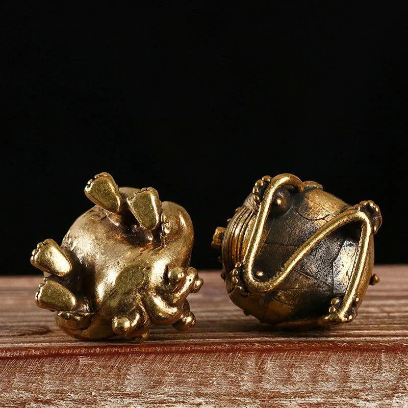 Two ornate gold objects on a wooden surface with a dark background